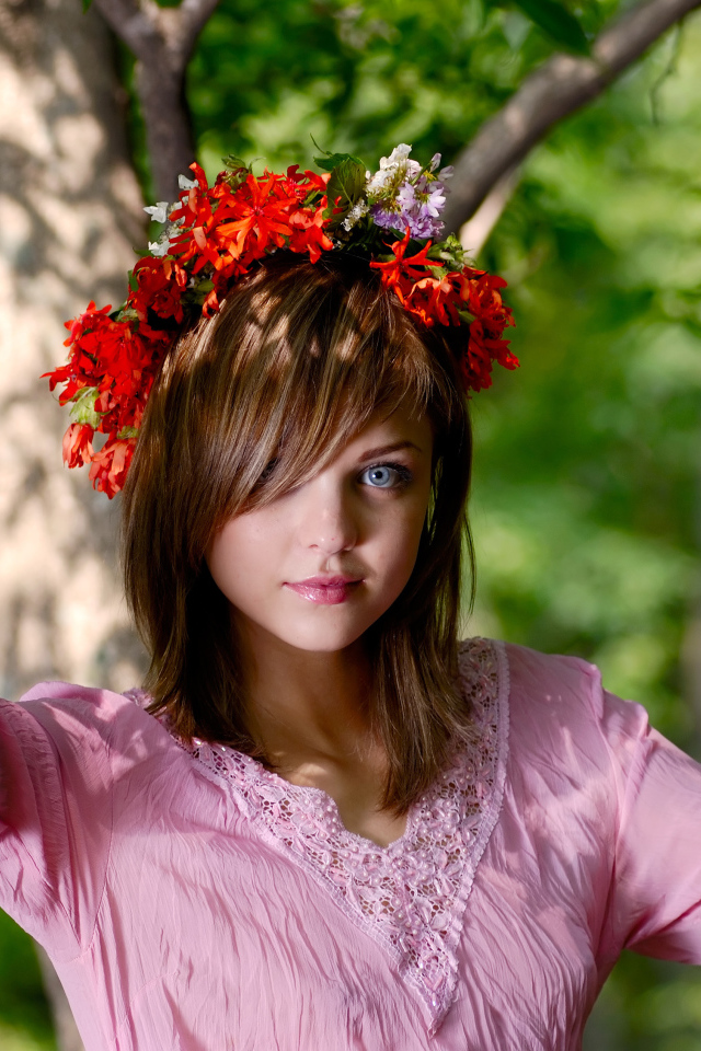 Молодая милая голубоглазая девушка с венком на голове у дерева