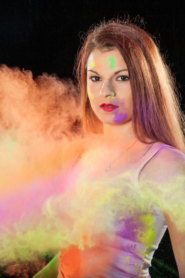 Молодая девушка в пыли от разноцветной краски 