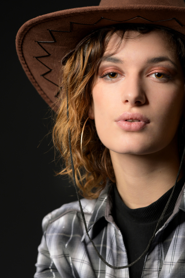 Молодая девушка в ковбойской шляпе на сером фоне