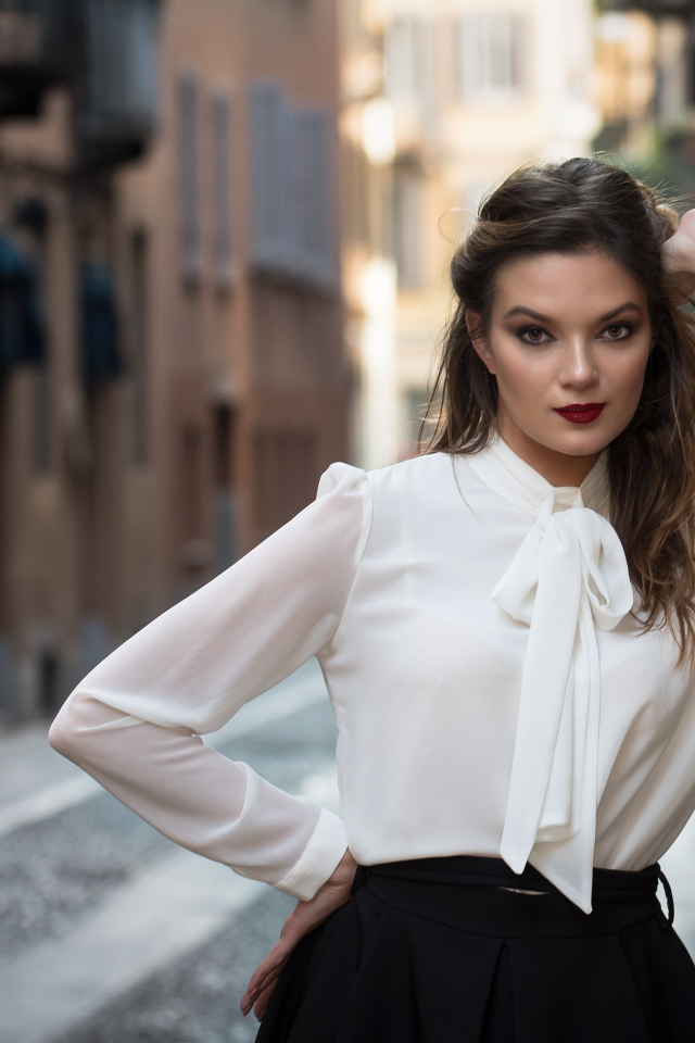 Молодая девушка в белой рубашке у стены