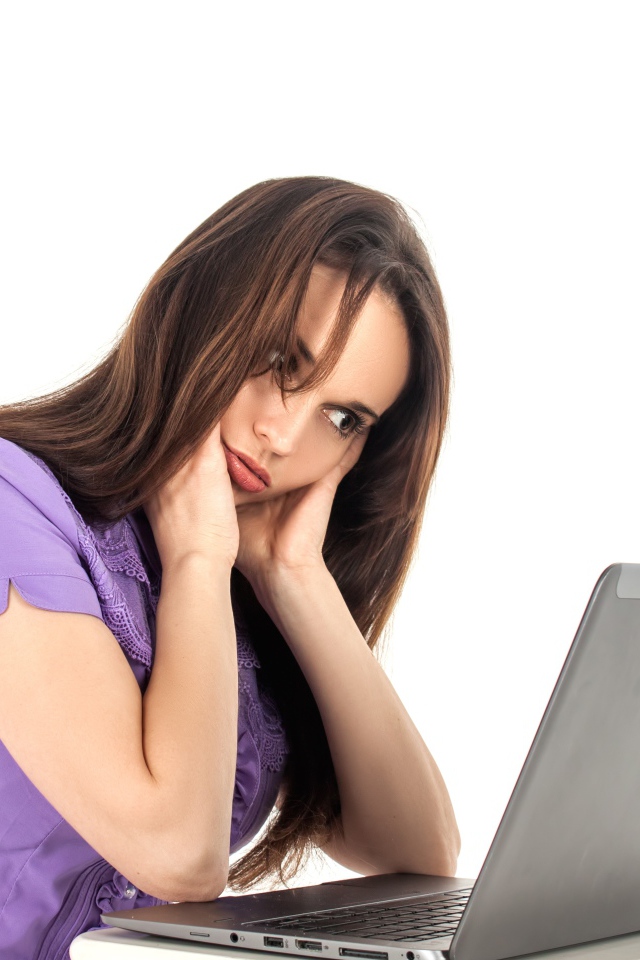 Молодая девушка сидит за ноутбуком на белом фоне