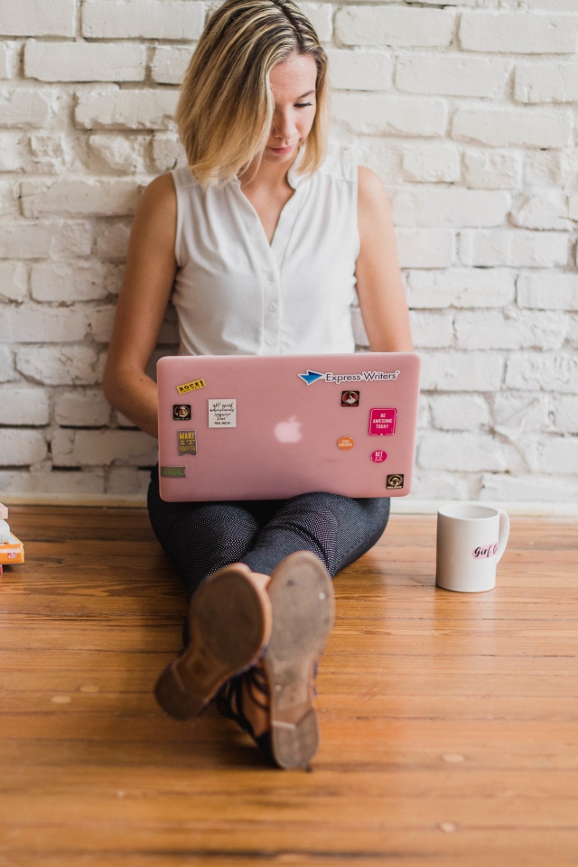 Молодая девушка студентка с ноутбуком и книгами у стены