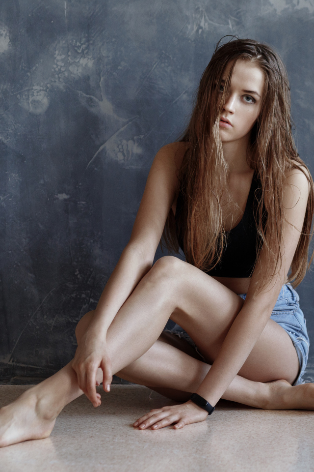 Молодая девушка с мокрыми волосами сидит у стены 