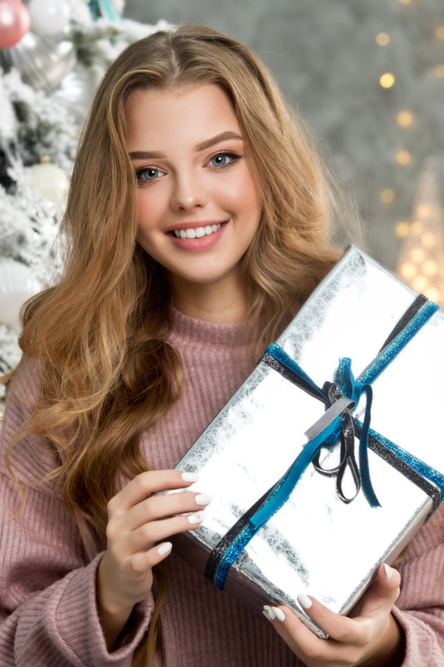 Красивая девушка с подарком у елки на новый год 