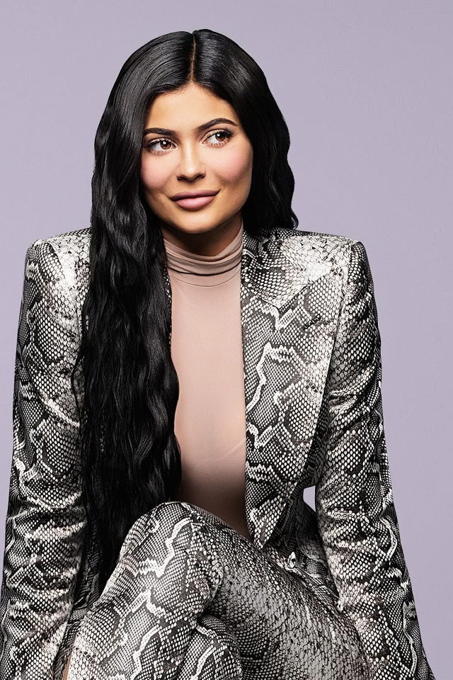 Длинноволосая модель Кайли Дженнер в костюме на сером фоне