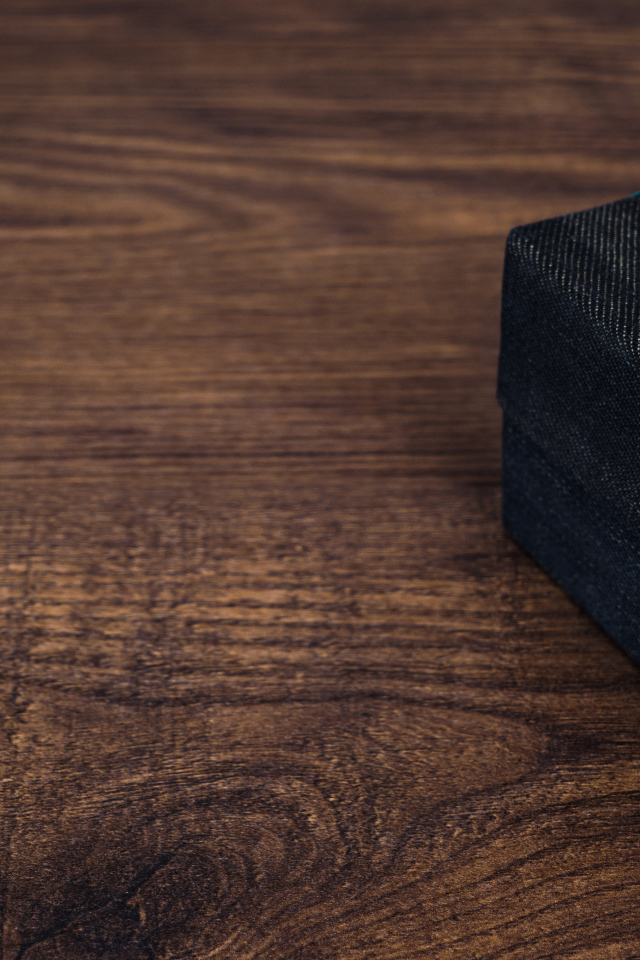 Подарок с синим бантом на деревянном столе 