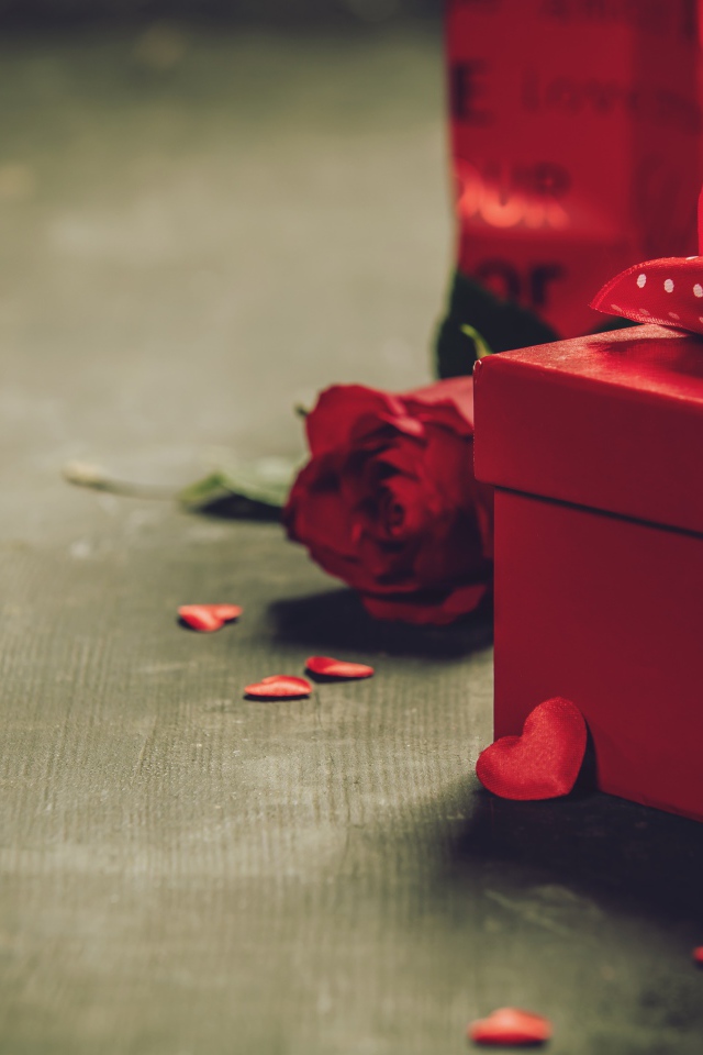 Red boxes with gifts on a table with a rose