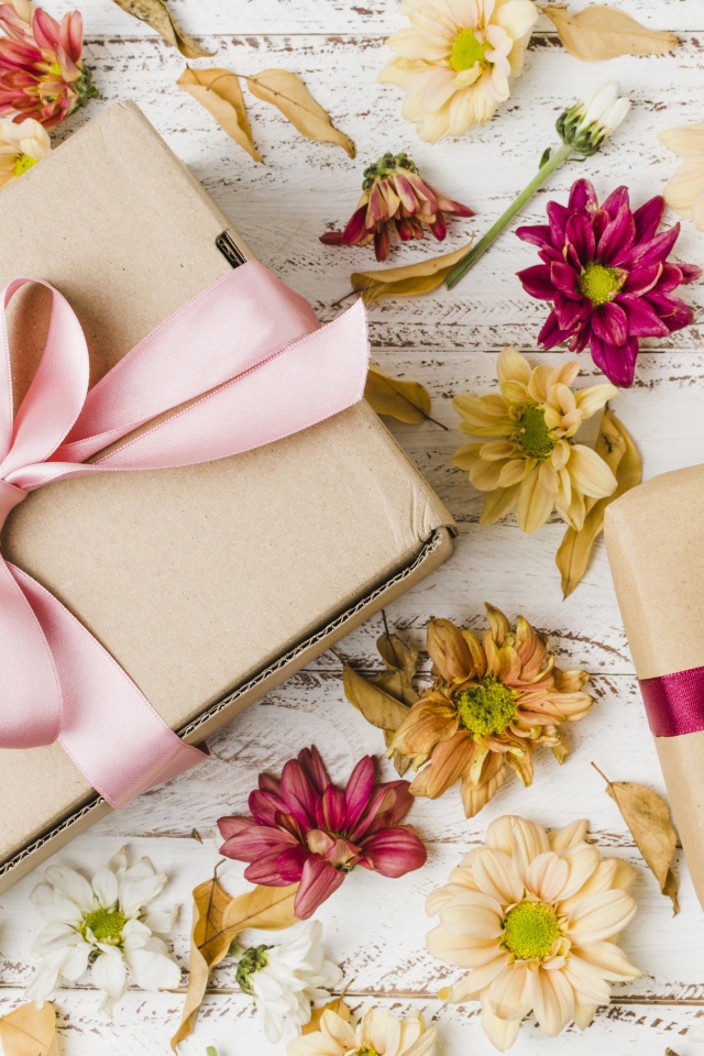 Two boxes with gifts on a table with chrysanthemum flowers