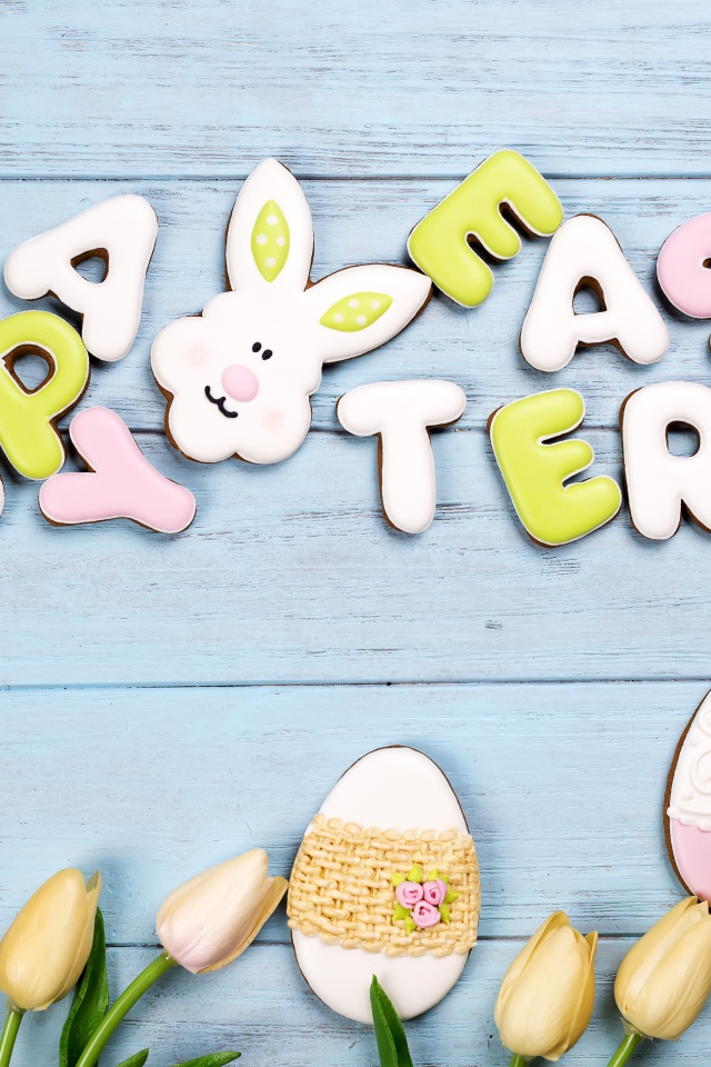 Красивое пасхальное печенье на столе с тюльпанами 