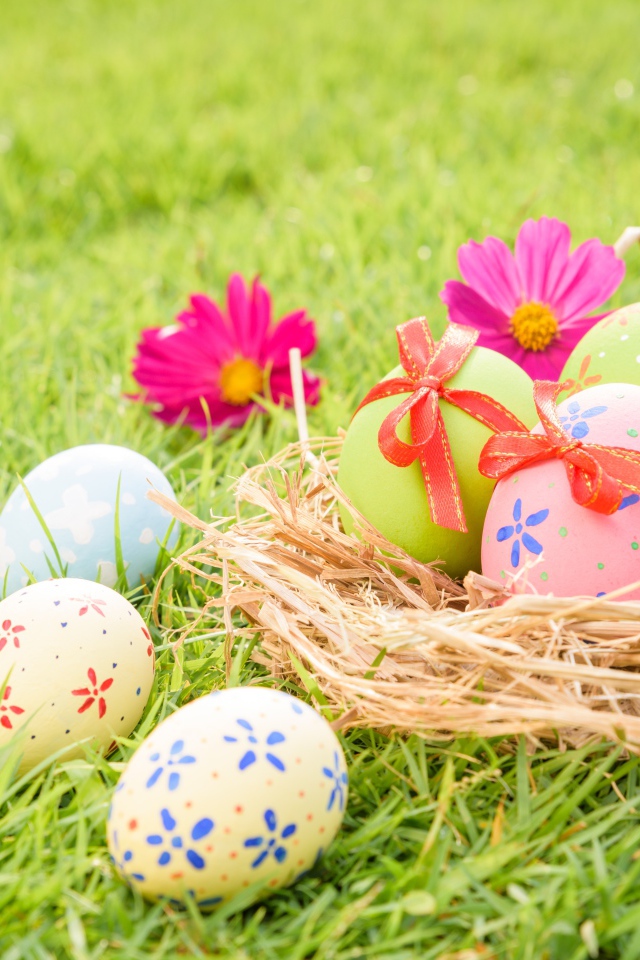 Разноцветные яйца в гнезде на зеленой траве на Пасху