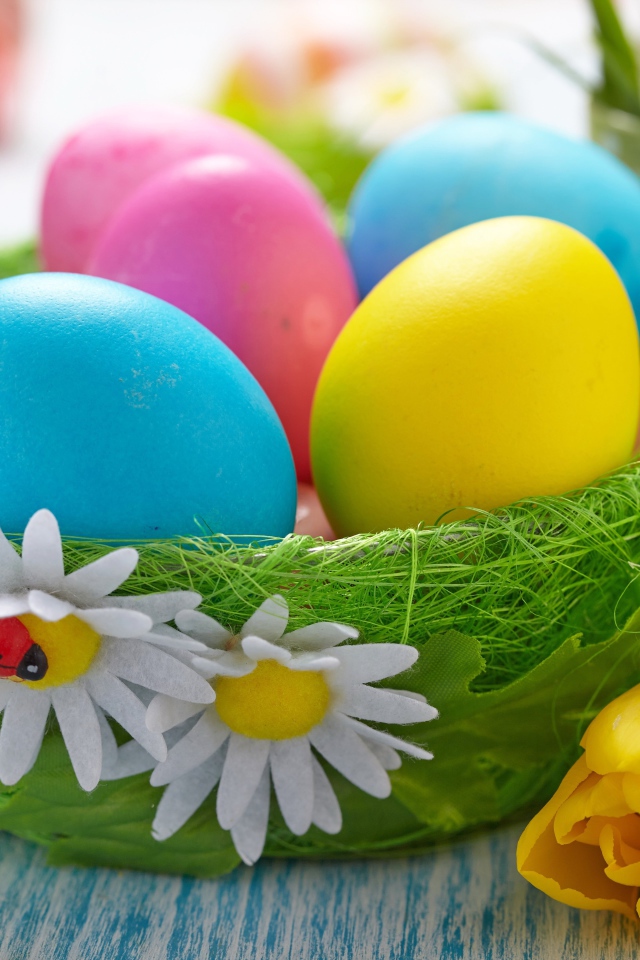 Разноцветные яйца на столе с тюльпанами на Пасху