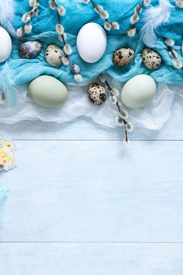 Яйца на ткани с ветками вербы на столе