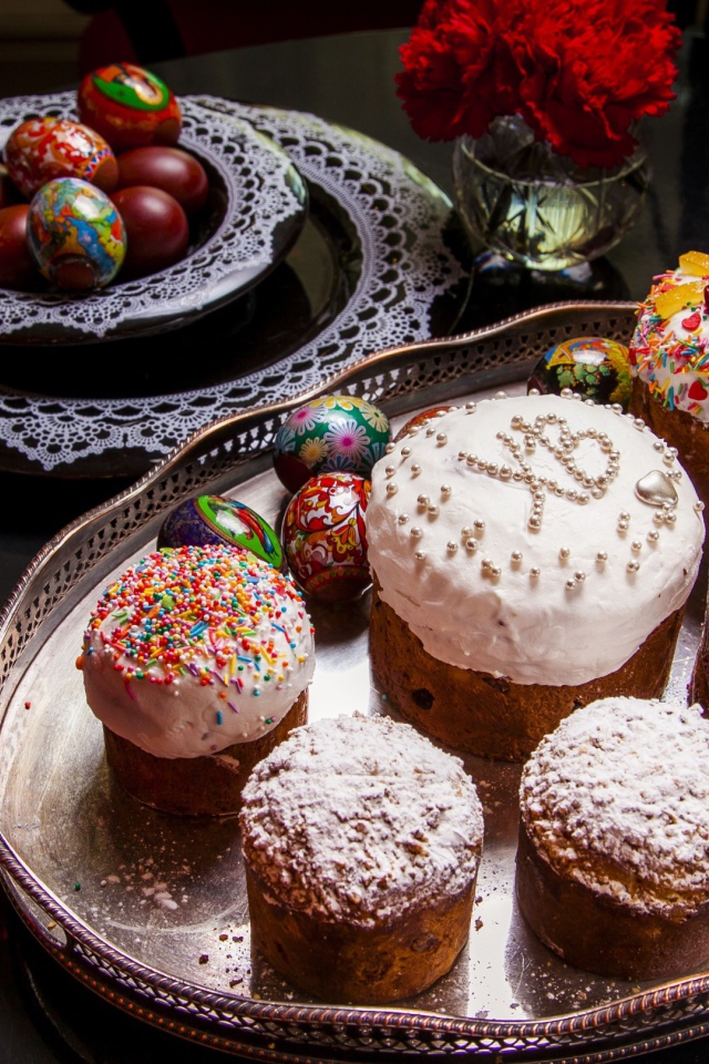 Много куличей на столе с гвоздиками и крашеными яйцами на праздник Пасха