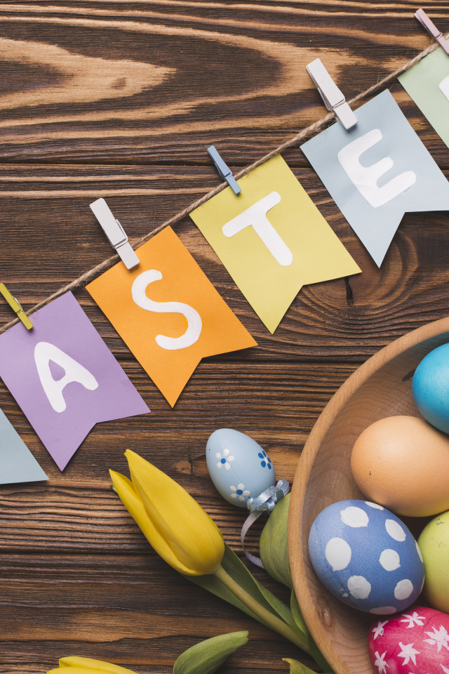 Надпись Пасха на столе с крашеными яйцами и тюльпанами