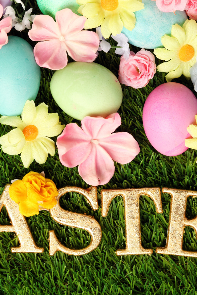 Надпись на траве с разноцветными яйцами и цветами на Пасху