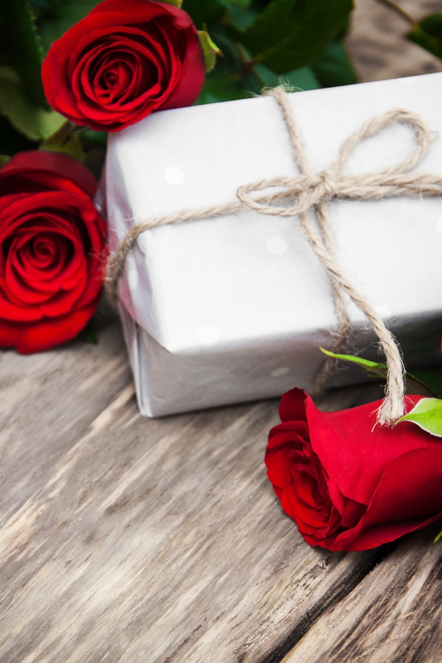 Букет красных роз на столе с подарком на 8 марта