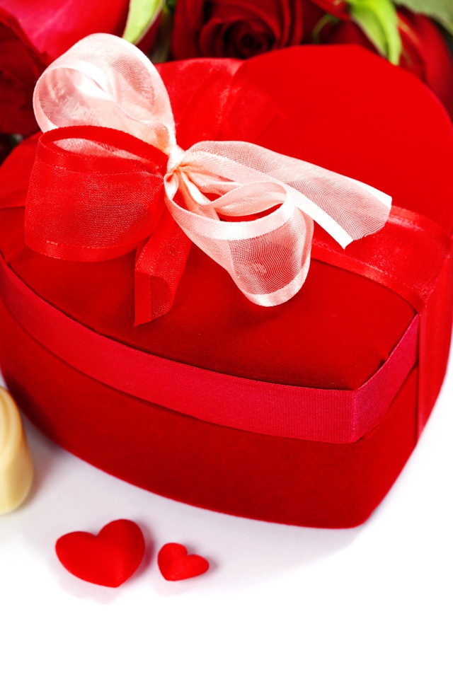 Красная коробка в форме сердца на столе с розами и конфетами для любимой