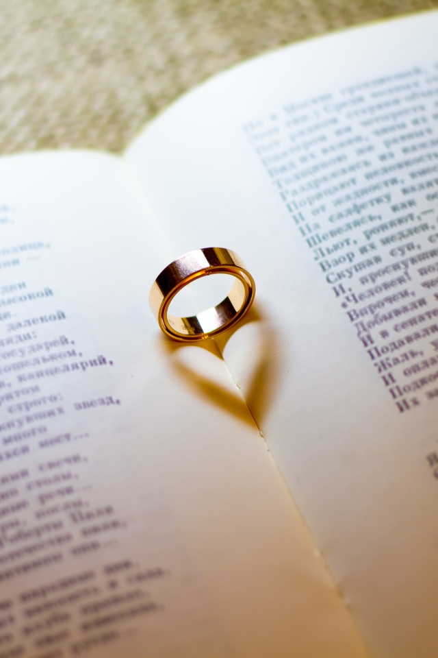 Золотое обручальное кольцо лежит на открытой книге