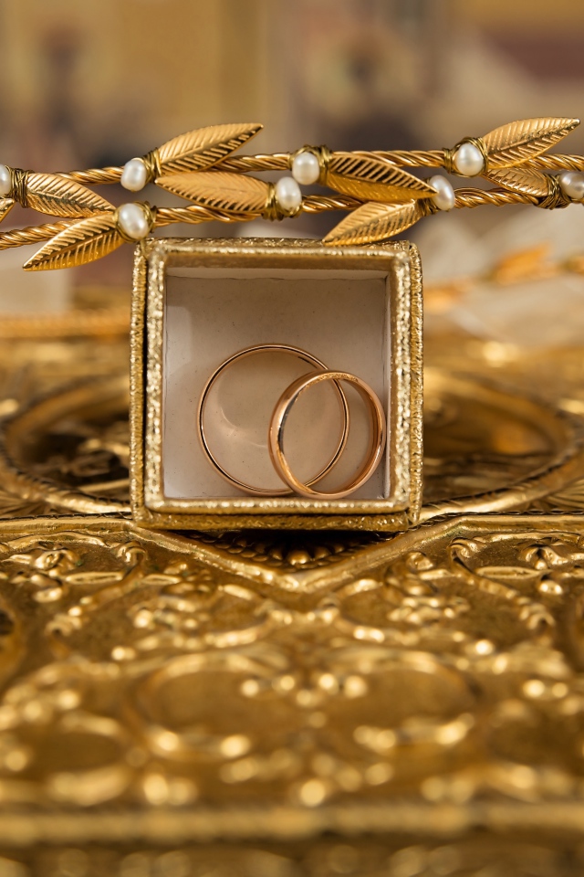 Два золотых обручальных кольца в коробке с венком 