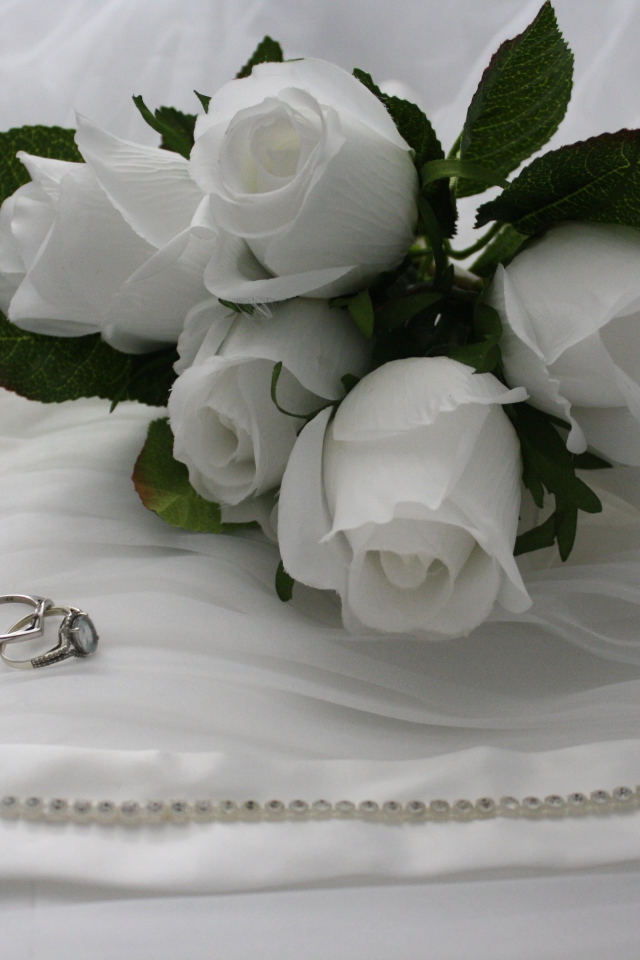 Белые бутоньерки с кольцами на белом покрывале 
