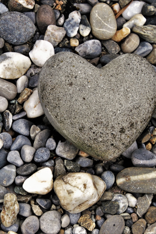 Большой камень в форме сердца лежит на морской гальке