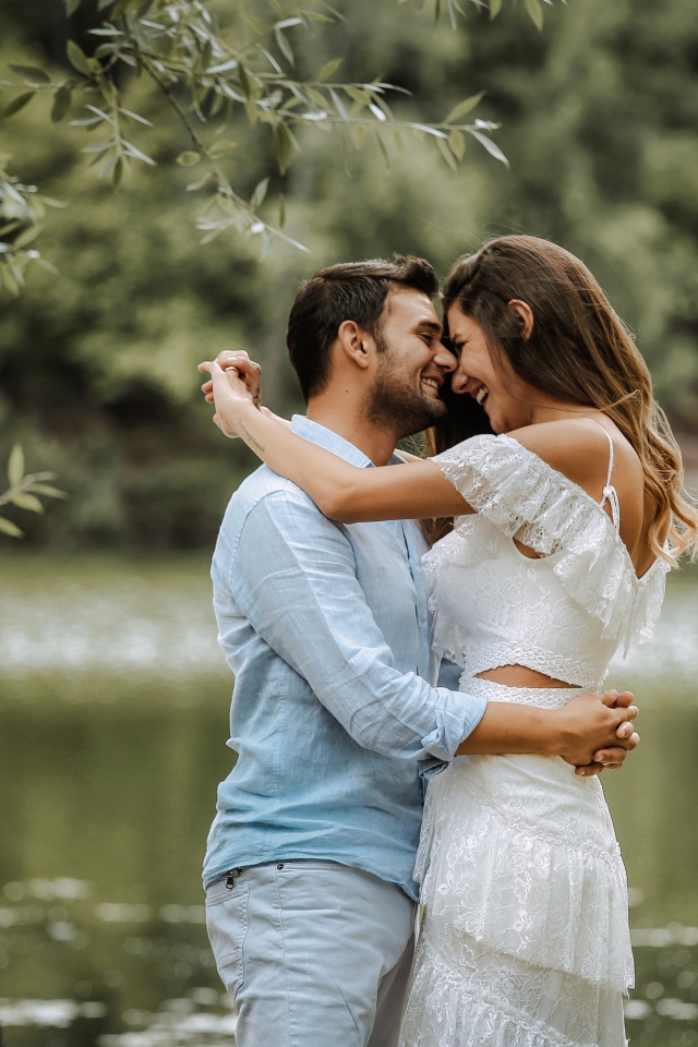 Влюбленная пара стоит у пруда в парке 