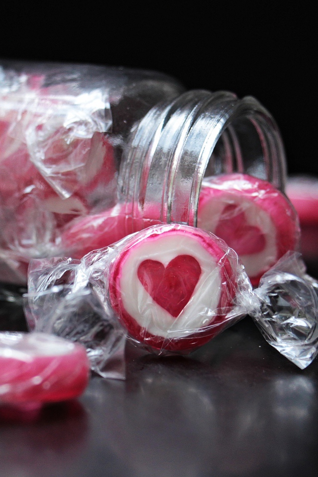 Конфеты с сердцем в стеклянной банке на черном фоне