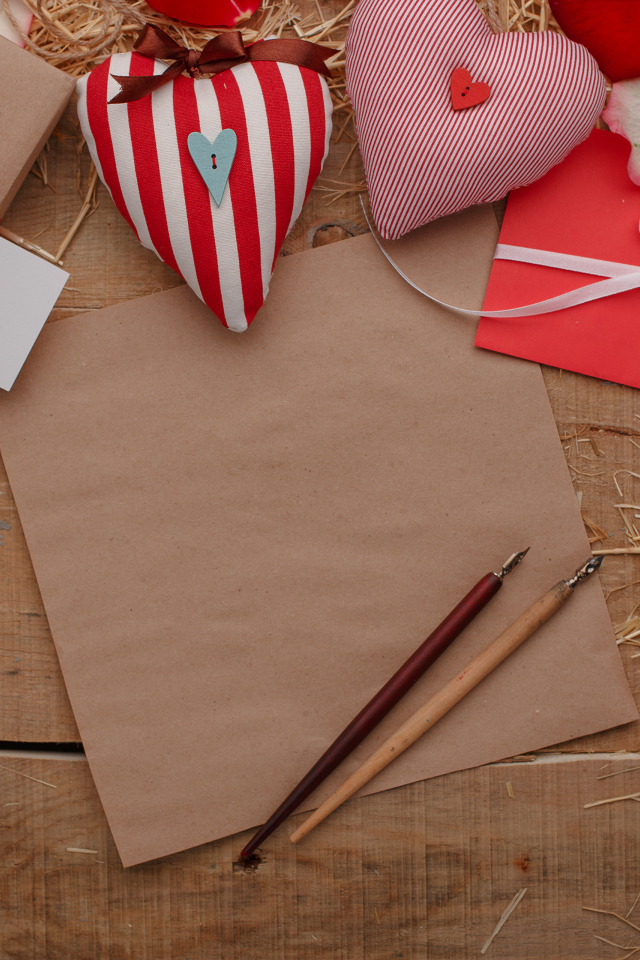 Сердечки из ткани на столе с бумагой и подарками 