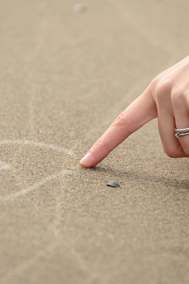 Девушка рисует сердце на песке 