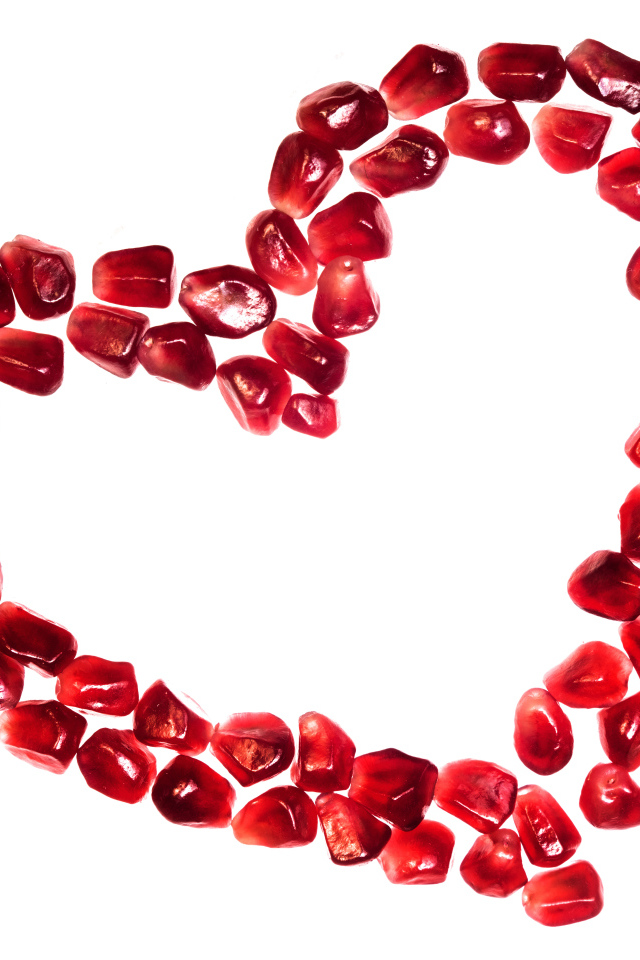 Сердце из гранатовых зерен на белом фоне