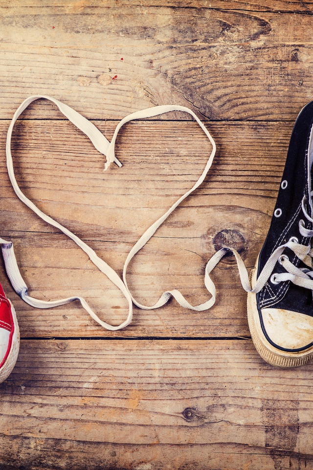 Сердце из шнурков кед на деревянном столе 