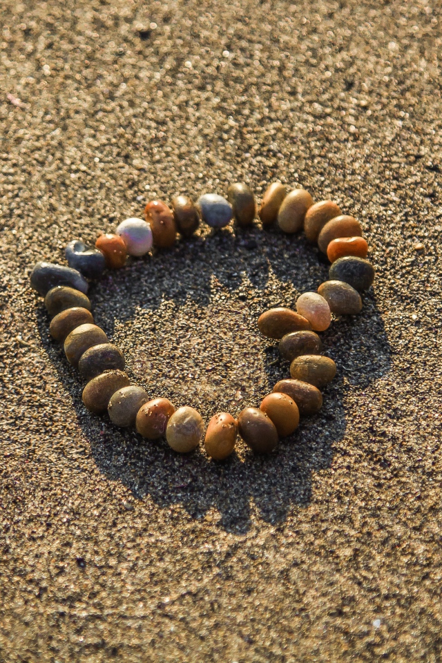 Сердце из мелкий морских камей на песке 