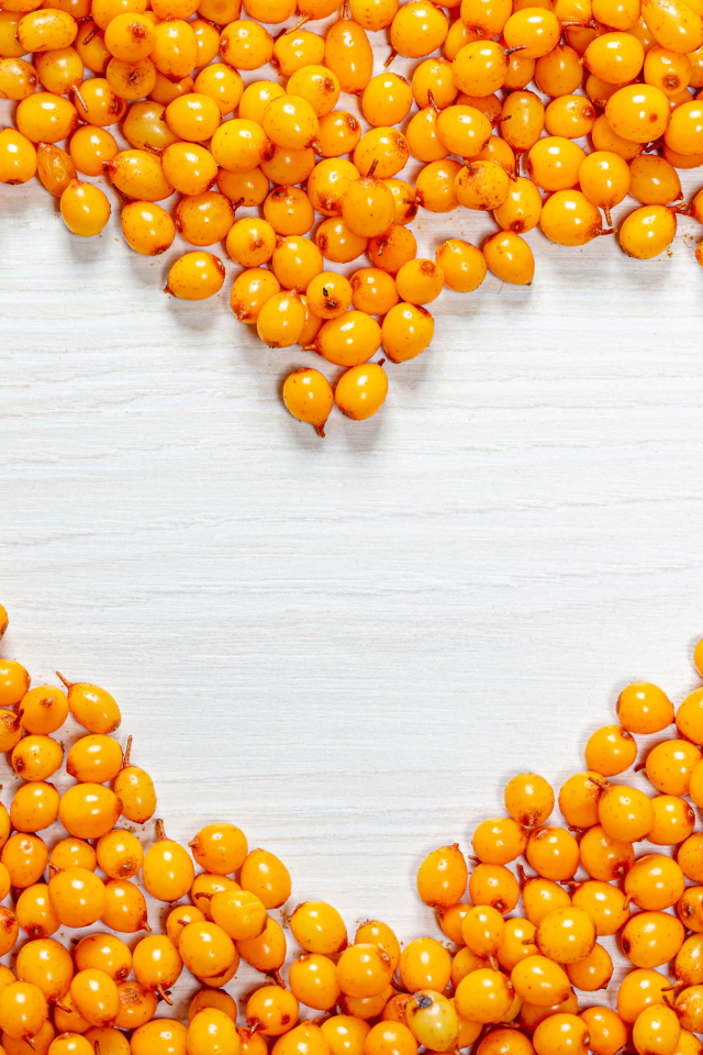 Сердце из ягод облепихи на столе 