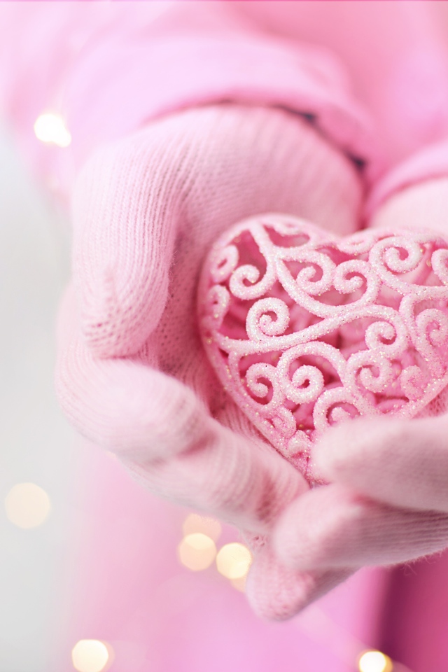 Розовое плетеное сердце в руках у девушки в перчатках 