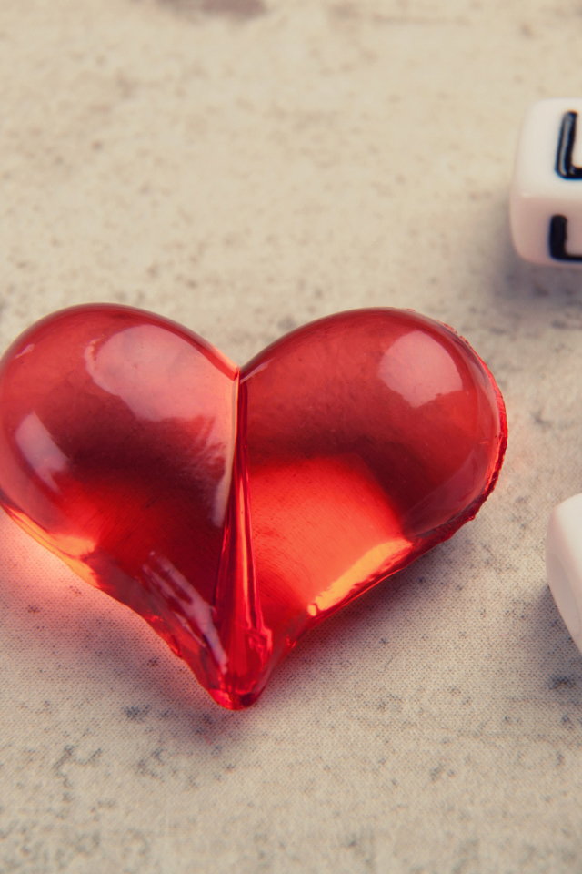 Красное стеклянное сердце на столе с кубиками