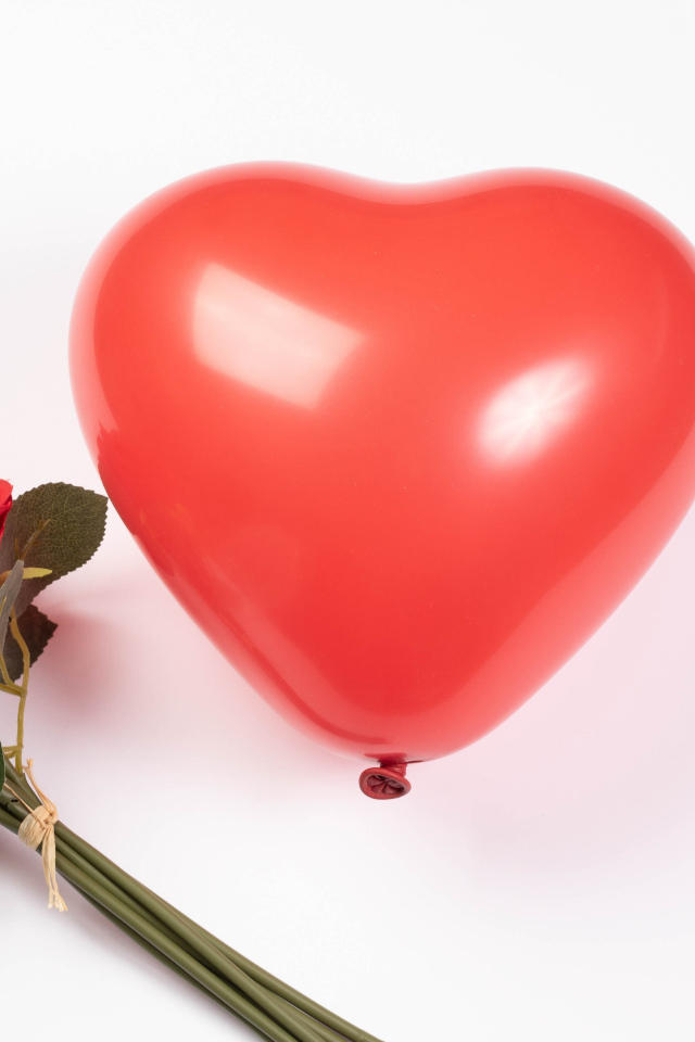 Красный шарик в форме сердца с букетом роз на белом фоне