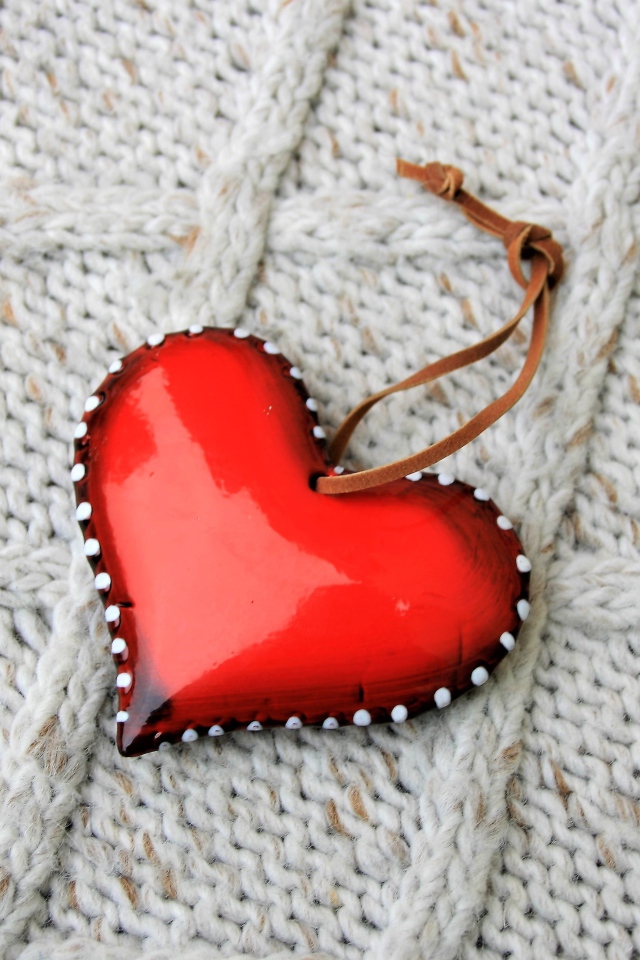 Красное сердце лежит на вязаном свитере 