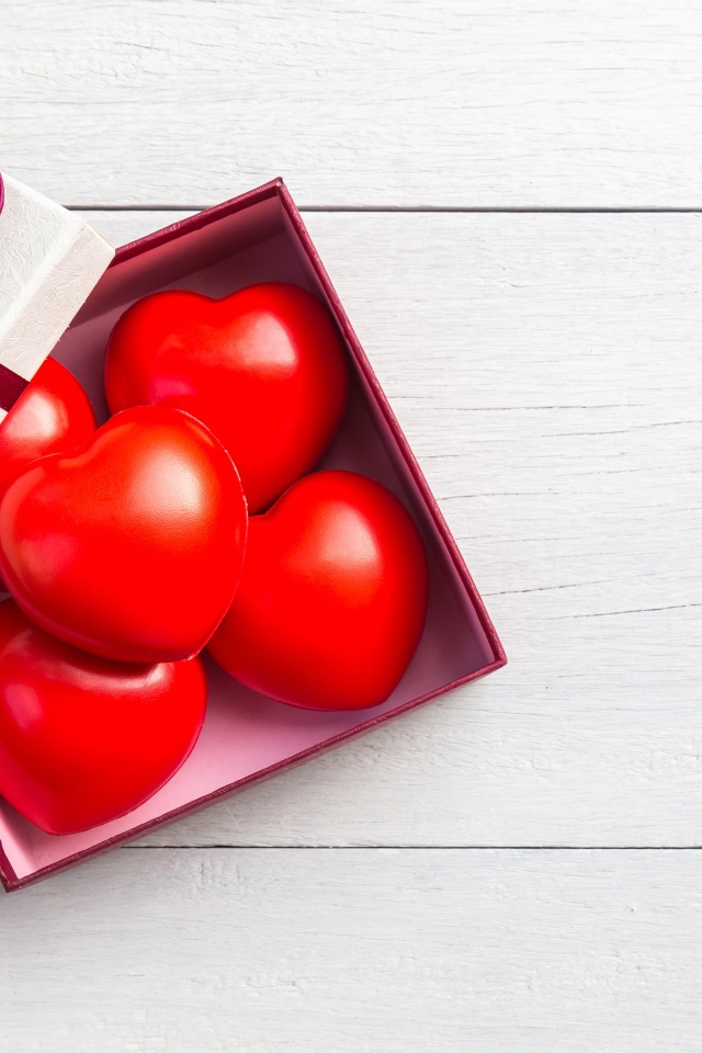 Красные сердечки в коробке на сером фоне