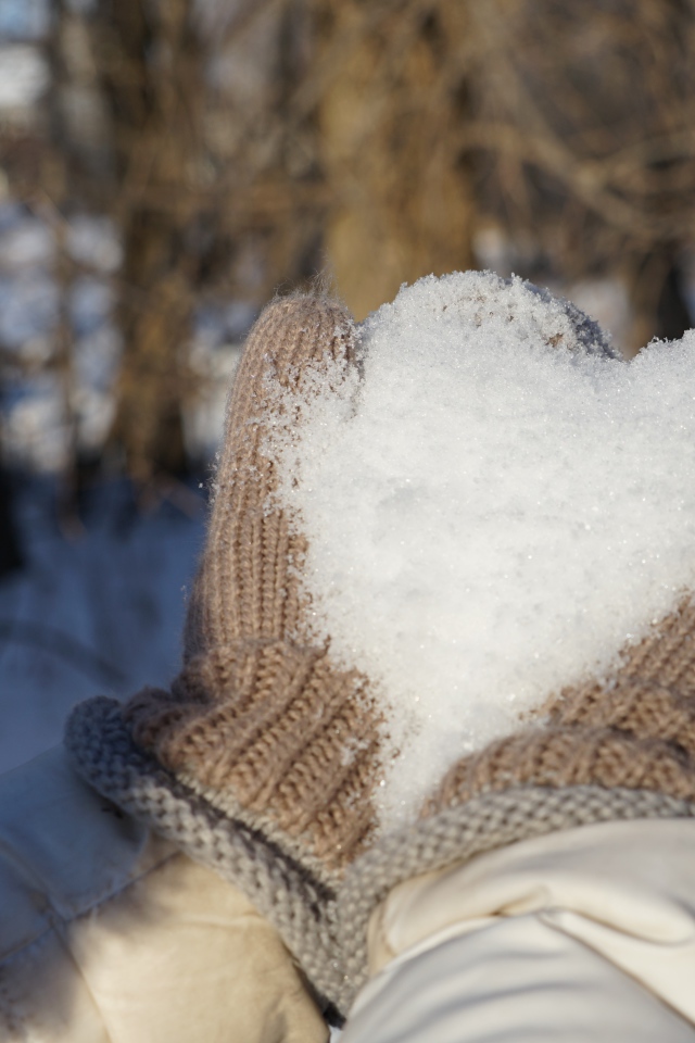 Снег в руках у девушки в перчатках 