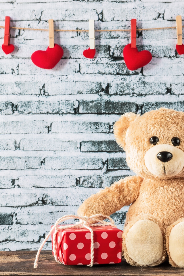 Медвежонок Тедди с подарками на фоне стены с сердечками