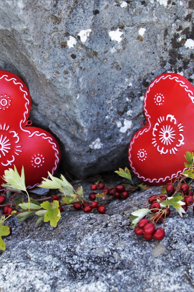 Два сердца лежат у камня с красными ягодами