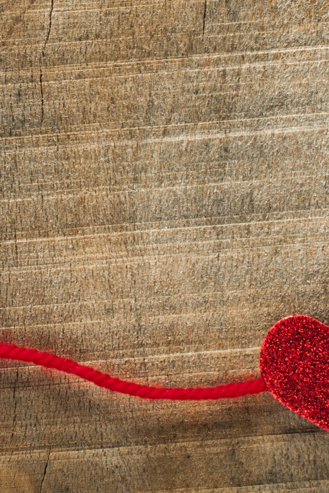 Два красных сердца со шнурком на деревянном фоне