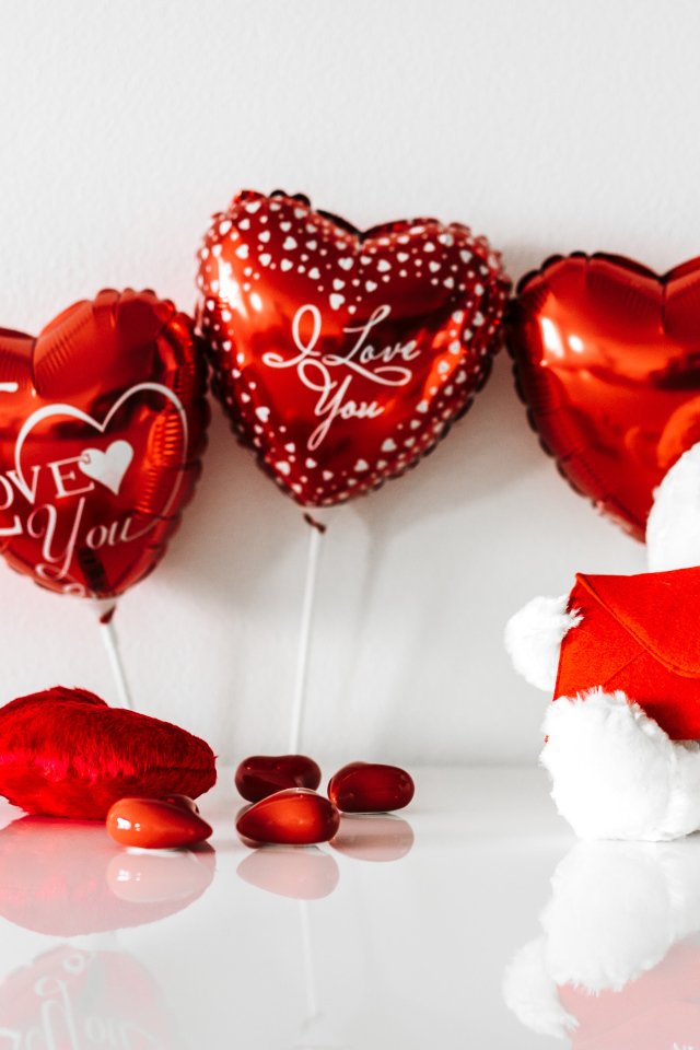 Белый мишка с подарками и шариками у стены