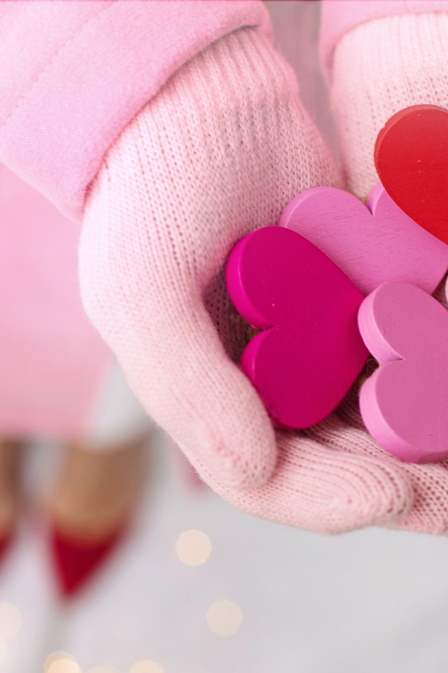 Деревянные сердечки в руках девушки в розовых перчатках 