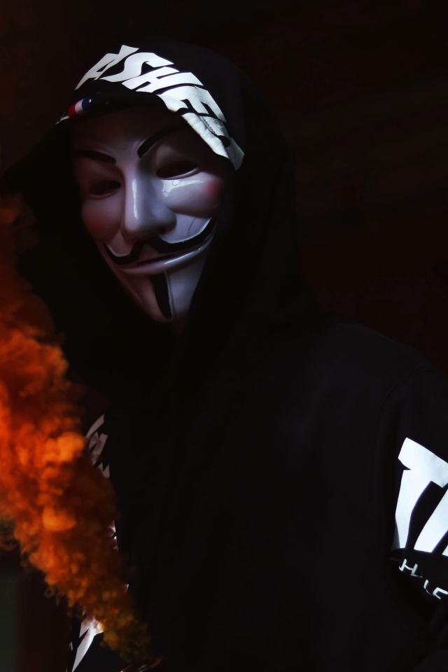 Мужчина в маске анонимуса с дымовой шашкой в руке