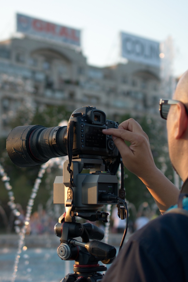 Мужчина снимает на камеру фонтан в парке