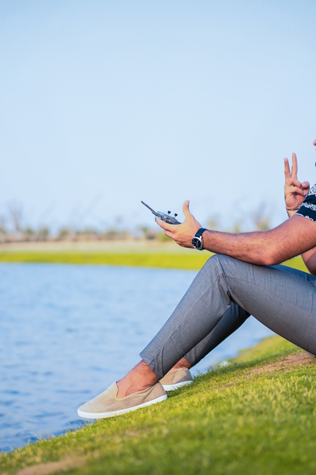 Мужчина запускает квадрокоптер над озером 