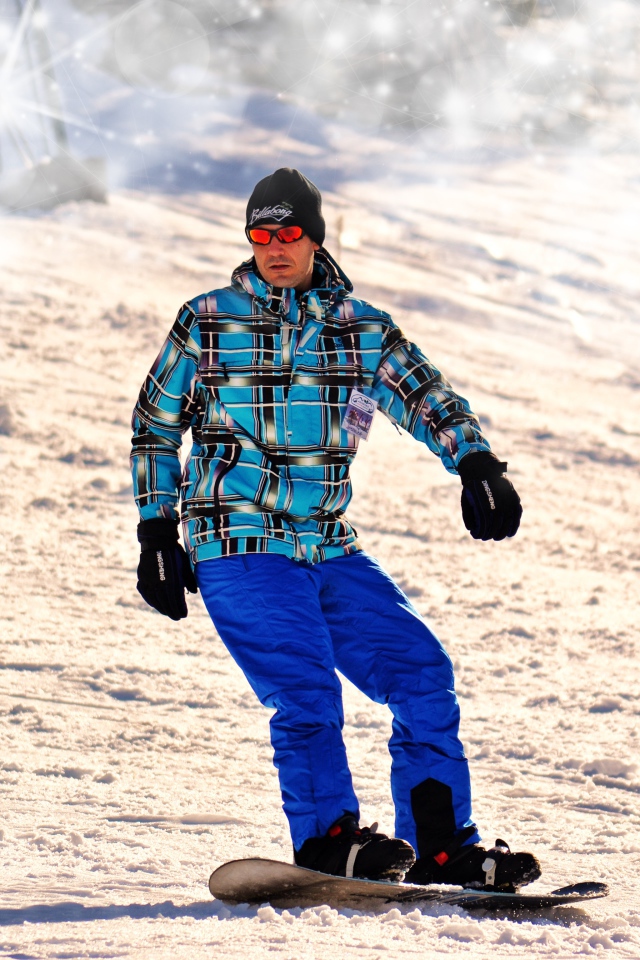 Мужчина сноубордист съезжает с горы 