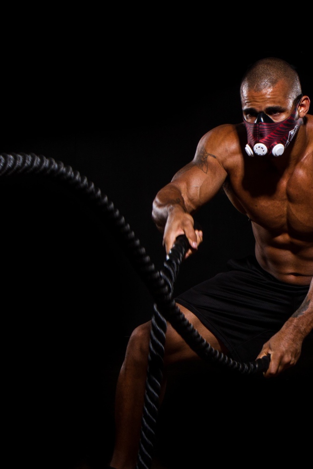 Накаченный мужчина в маске с канатом в руках 