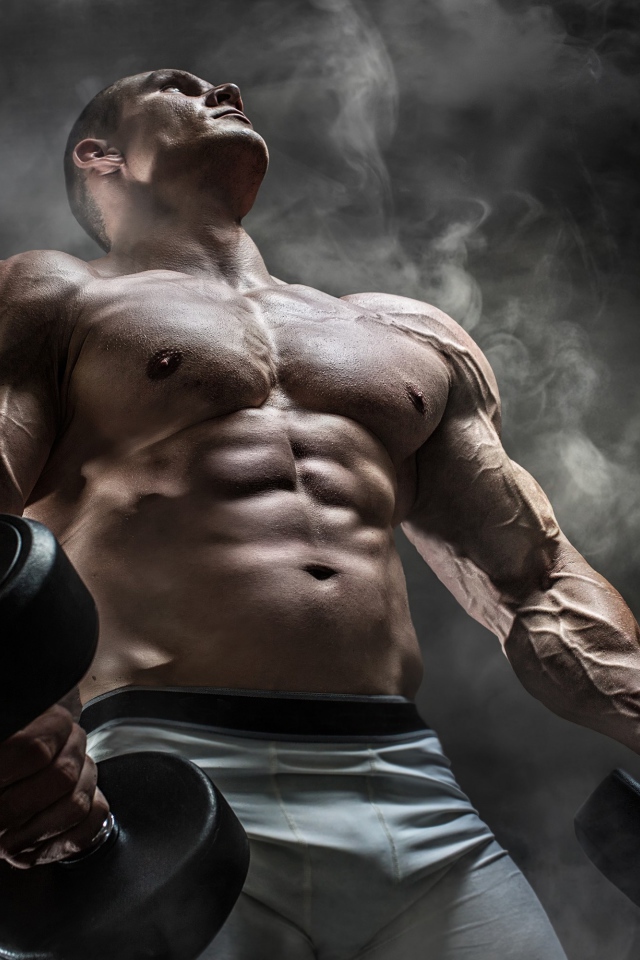 Мужчина бодибилдер с тяжелыми гантелями в руках